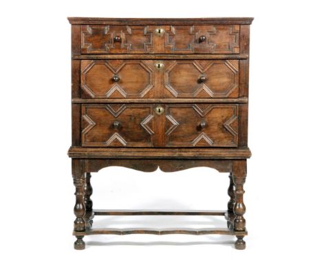 An oak chest of three graduated geometric panelled drawers in the 18th Century style, raised to a serpentine shaped stand, he
