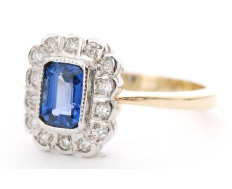 An 18ct hallmarked sapphire and diamond cluster ring, central emerald cut collar set sapphire within fourteen stone diamond s