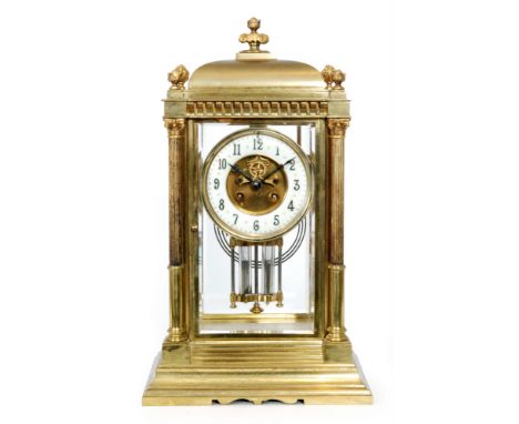 An early 20th Century brass mantle clock of classical form, glass sides united by pillars with mercury suspension pendulum, c