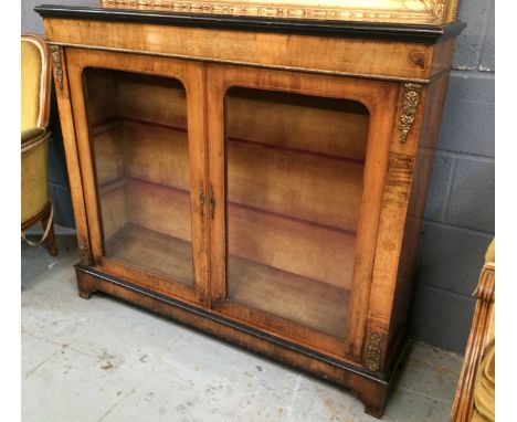 A Victorian walnut credenza with ebonised border trim and decorative gilt metal mounts, the double doors with arch-shaped gla