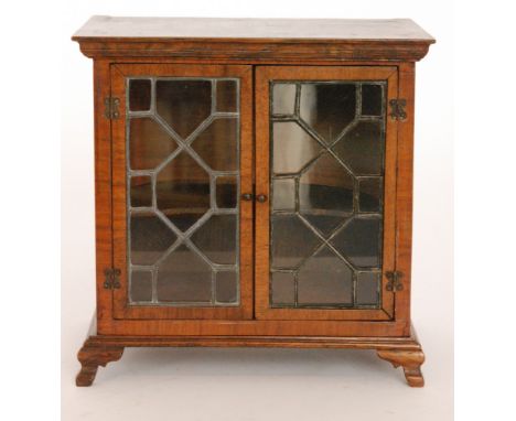 A 20th Century miniature crossbanded mahogany apprentice cabinet in the Chippendale style, enclosed by a pair of leaded light