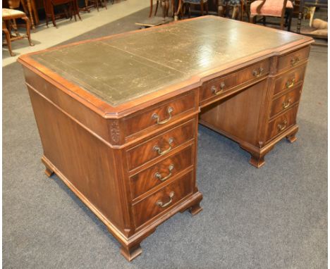 A 20th Century mahogany partners desk in the Georgian style, the inverted tooled leather top with canted corners over an arra