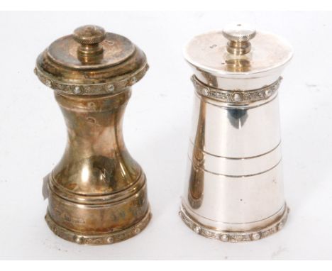 A hallmarked silver pepper grinder in the form of a milk churn and another similar example, both with Celtic border decoratio