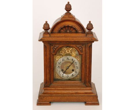 A late 19th to early 20th Century oak cased mantle clock with eight day striking movement on a gong, silvered chapter ring an