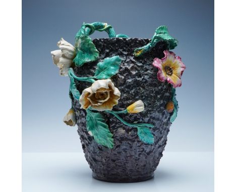 A 14"H Majolica-style vase featuring intricate applied floral motifs and a richly textured body. This handled vase showcases 