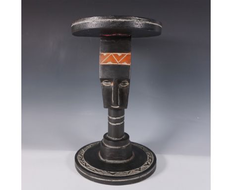 This hand-carved African wooden stool features a striking tribal motif with a stylized face as the central support. The seat 