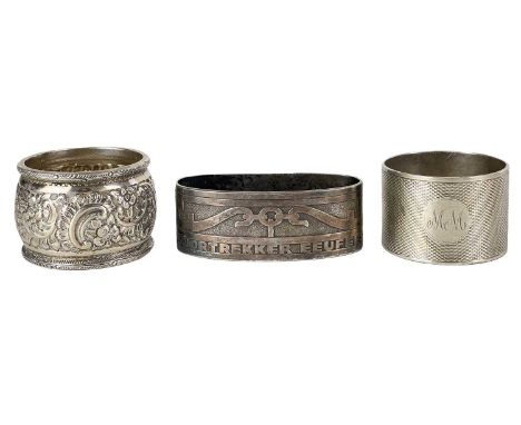 Three heavy silver napkin rings. Including a Victorian foliate scroll embossed ring, Sheffield 1901, an engine turned ring, S