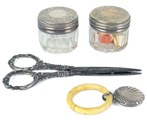 A pair of Victorian silver lidded glass jars, a pair of silver-handled scissors and a baby's rattle. The jar lids hallmarked 