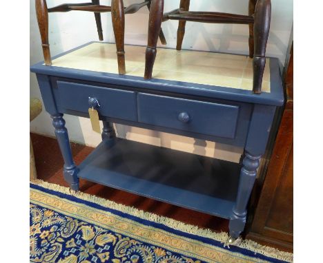 A blue pained pine kitchen table, with tile top, raised on turned legs and castors, H.82 W.110 D.50cm