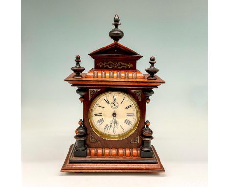 Carved walnut clock from late 19th century, early 20th has spires on top surrounded by metal applied design and carved detail