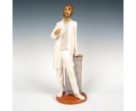 The figurine depicts a young man dressed in a doctor's coat wearing a stethoscope. This item has its original box which measu