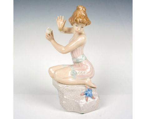 This charming figurine captures a young woman in a moment of surprise, crouched on a rock in her bathing suit. Lladro backsta