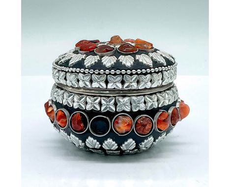 A stunning silver-tone metal round covered box painted black. Decorated with embossed flowers, and what is believed to be eit