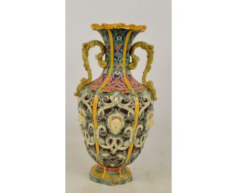 A Copeland majolica footed vase of baluster form with flared rim and twin scroll decorated handles, the panelled body decorat