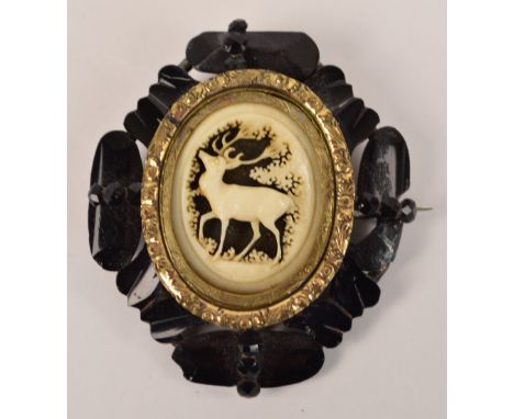 A Victorian jet decorated mourning brooch centred within a bone carved panel depicting a stag, within yellow metal border, 6.