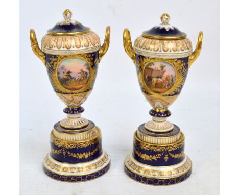 A near pair of Vienna porcelain twin handled urns and covers on knopped stems above stepped cylindrical bases with tapering p