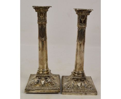 A pair of George V hallmarked silver candlesticks modelled as Corinthian columns, embossed with swags to the stems, with urns