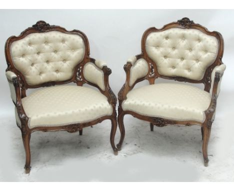 A pair of Victorian walnut elbow chairs with button upholstered back and carved foliate scroll frame, on cabriole legs with s