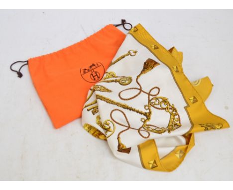 HERMES; a silk head scarf in "Les Cles" pattern (The Keys) with burnt yellow border, 89 x 89cm, in an Hermes dust cover. COND