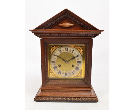 A c.1900 oak and walnut mantel clock with pediment and plinth decorated with egg and dart frieze, the brass dial with silvere