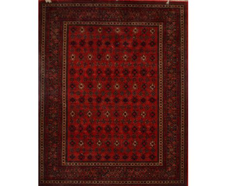 A carpet decorated with geometrical motifs within an ornamental border on red ground, 237 x 168cm.