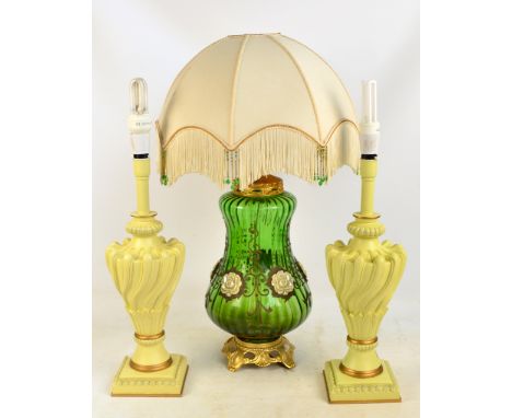 A green glass globular lamp base with applied floral motifs on a gilded stand with a fringed and beaded shade, height excludi