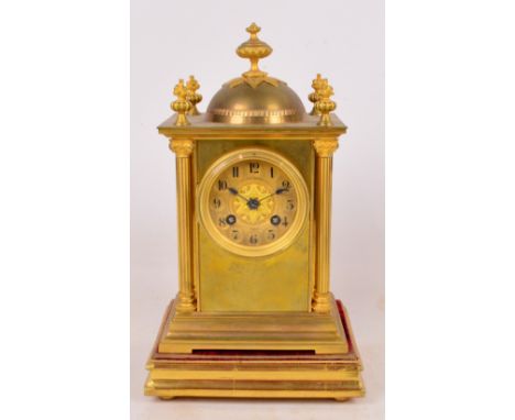 A late 19th century gilt brass mantel clock, the urn set domed surmount set with four floral capped finials above circular di