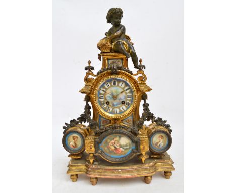 A late 19th century French gilt metal and porcelain eight day mantel clock surmounted with a cherubic figure above enamel cir