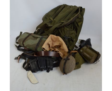 An army backpack, a camouflage ground sheet, belt with flask attachments, various other belts, etc.