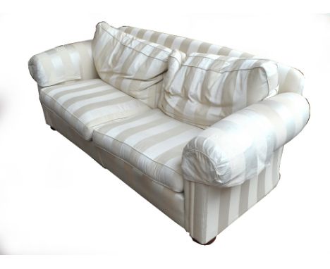 A large modern cream upholstered three seater sofa.