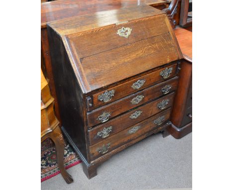 An early to mid 19th century oak bureau with elaborate brass escutcheon, the fall front enclosing fitted interior above four 
