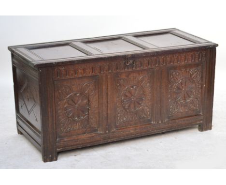 A large late 17th century oak coffer, the triple panelled top above carved panel front, raised on stile supports, length 142c