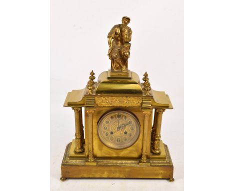 A late 19th century lacquered brass mantel clock, the shaped case centred with a seated figure above circular dial set with A