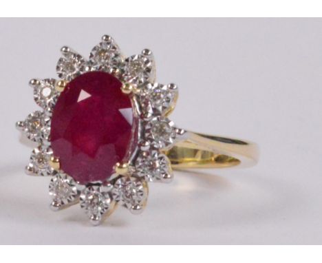 A 9ct yellow gold ruby and diamond ring, the large oval ruby set with a stepped border of twelve diamonds in claw setting, ri