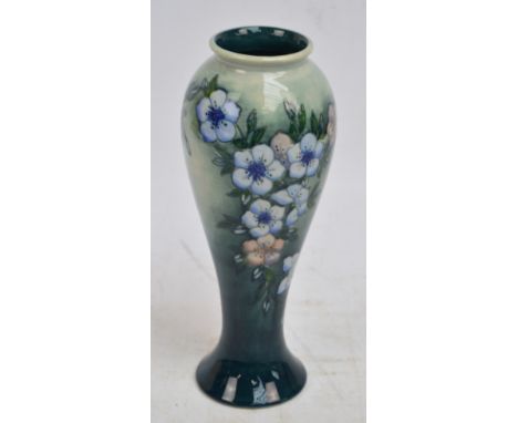 A William John Moorcroft vase of baluster form tube line decorated with blue flowers on two tone dark green ground, impressed