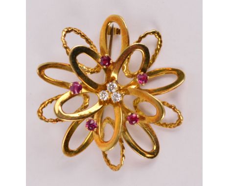 An 18ct yellow gold diamond and ruby set pierced circular floral brooch centred with three small diamonds within a border of 