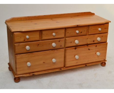 A pine chest of drawers with two formations of two short above two long drawers with crackle glazed ceramic handles on turned