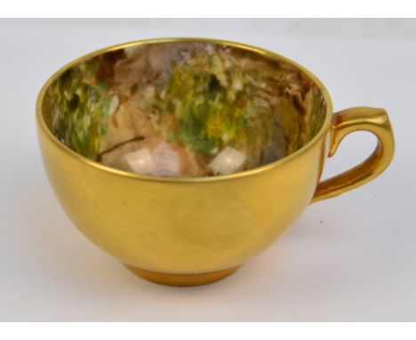 A small Royal Worcester cabinet cup of squat form with gilding to the outside and hand painted with berries and peaches to th