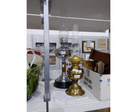 A chrome and treen oil lamp on ceramic base and another brass oil lamp 