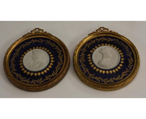 A pair of 19th century French gilt metal mounted porcelain portrait roundels, centred by bisque cameo profile portraits of of