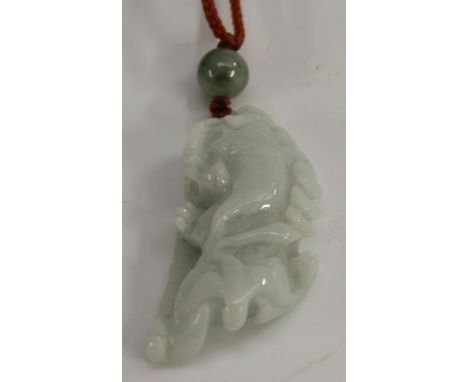 A Chinese pale celadon jade pendant, carved as a temple lion, 5cm long
