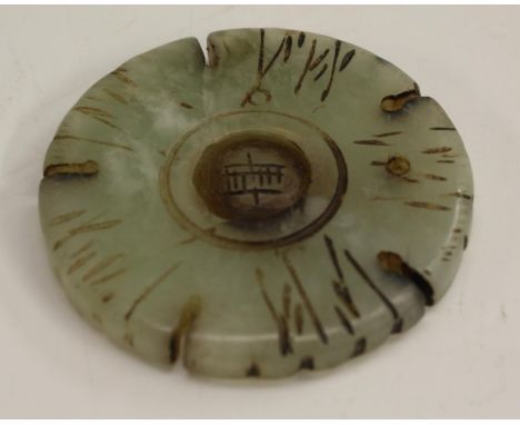 A Chinese pale celadon jade circular talisman or amulet, the disc edge in relief with five notches and the field incised with