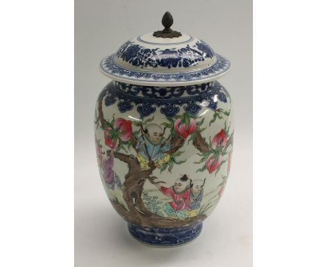 A Chinese Republican period ovoid jar and cover, painted in polychrome with boys playing in a peach tree, underglaze blue lap