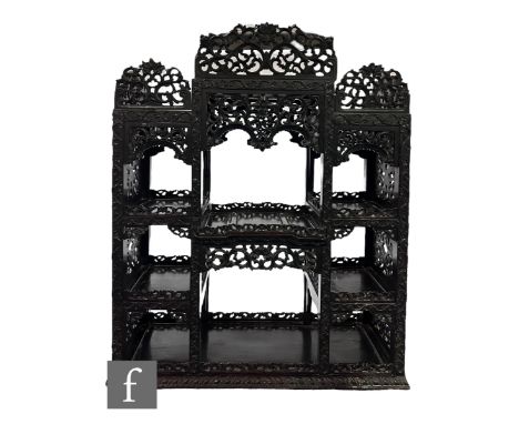 A late 19th Century Anglo Indian carved harwood/Padouk floorstanding cabinet, the pierced top rail over a deep central sectio