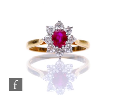 An 18ct hallmarked ruby and diamond cluster ring, central oval ruby, length 5mm, within a border of eight brilliant cut diamo