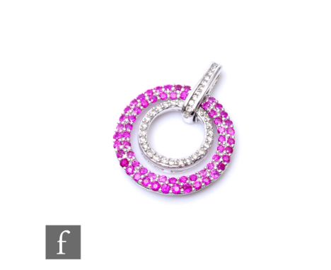 A 9ct hallmarked white gold ruby and diamond circular pendant, a double row of rubies encompassing a row of diamonds, total w