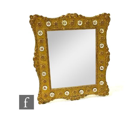 A 20th Century scroll gilt framed wall mirror mounted with miniature ceramic plaques with scenes after Fragonard, 72cm x 62cm