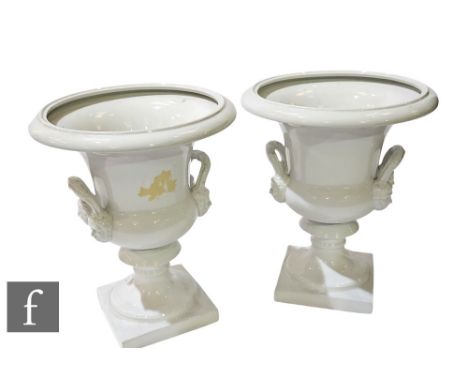 A pair of contemporary large white ceramic campana urns, possibly Italian, each with twin mask mounted handles, over integral