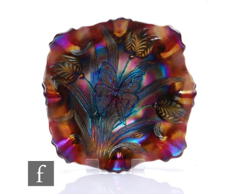 An early 20th Century Carnival glass four footed bowl with deep body and wave edged rim by Dugan, relief moulded to the centr
