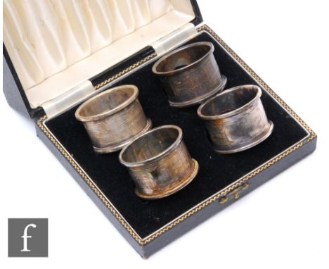 A cased set of four hallmarked silver circular napkin rings each with engine turned decoration, Birmingham 1950,&nbsp;G Bryan